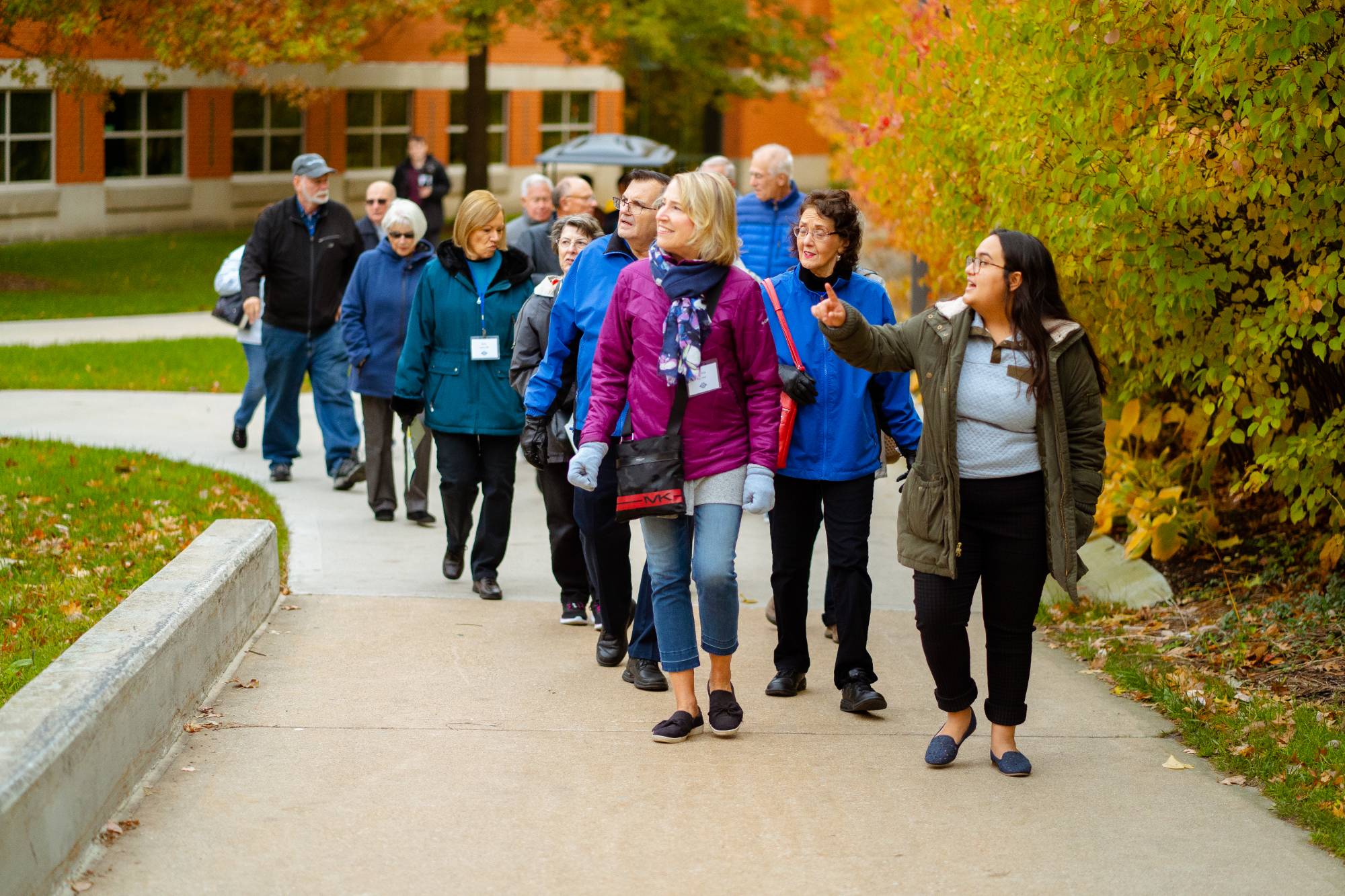 Alumni walk along a path on a campus tour led by a guide